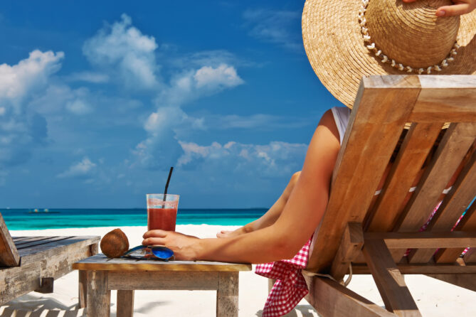 A woman looking at the sea while holding a drink to depict how to spend your free time.