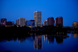 Richmond, Virginia city skyline over the James River as seen at night with reflections in the water.