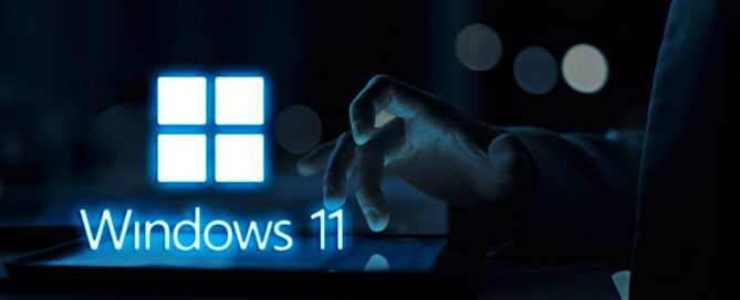 Hand interacting with a tablet displaying the Windows 11 logo in a dark, professional setting